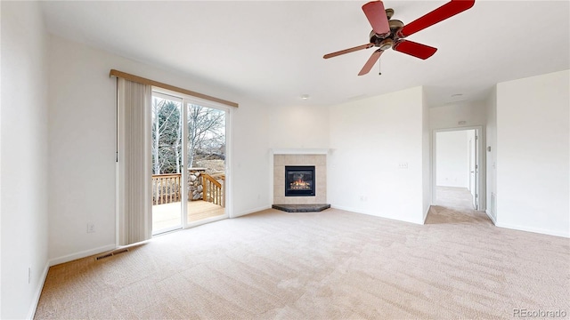 unfurnished living room featuring carpet floors, a fireplace, visible vents, ceiling fan, and baseboards