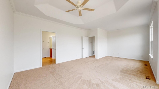 unfurnished bedroom with light carpet, baseboards, a tray ceiling, and ornamental molding