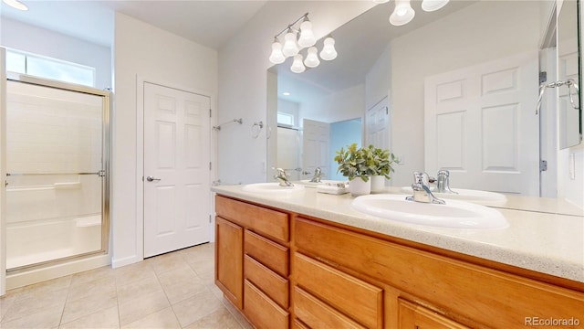 full bath with double vanity, a sink, a shower stall, and tile patterned floors