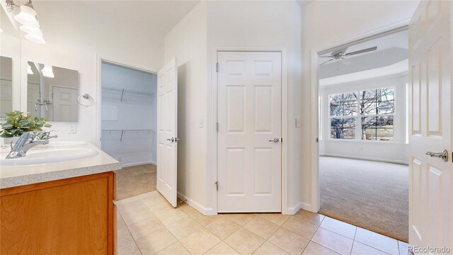 bathroom featuring double vanity, a ceiling fan, tile patterned floors, a spacious closet, and a sink