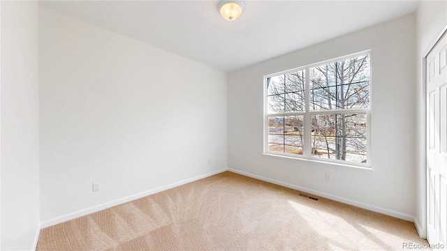 spare room featuring carpet floors, visible vents, and baseboards