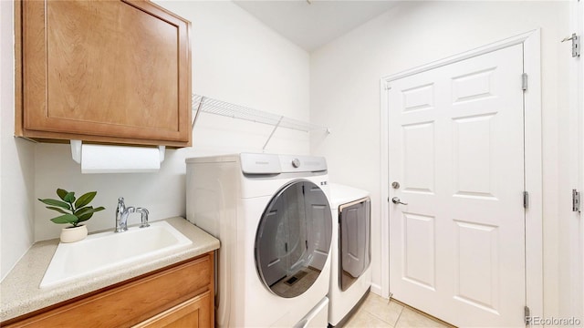 clothes washing area featuring separate washer and dryer, light tile patterned flooring, a sink, and cabinet space