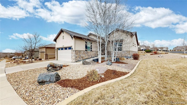 view of front facade featuring a garage, stone siding, driveway, and stucco siding