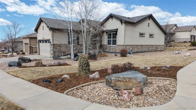 view of front of property featuring stone siding, concrete driveway, an attached garage, and stucco siding