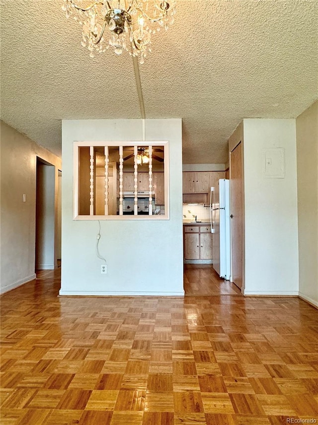 unfurnished living room featuring a textured ceiling, parquet flooring, and a chandelier