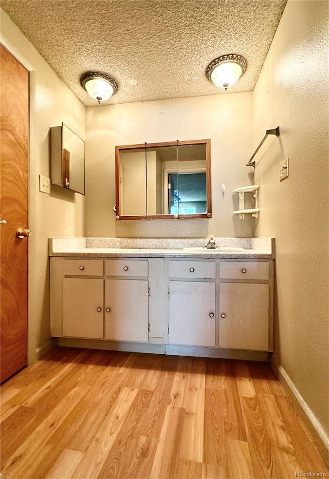 bathroom with hardwood / wood-style flooring, a textured ceiling, and vanity