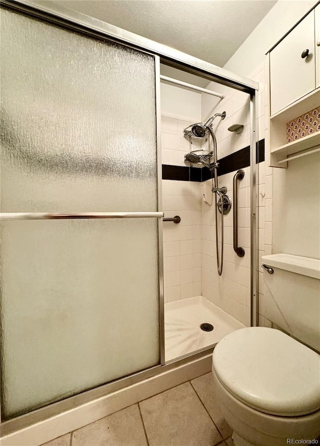 bathroom featuring toilet, walk in shower, and tile patterned flooring