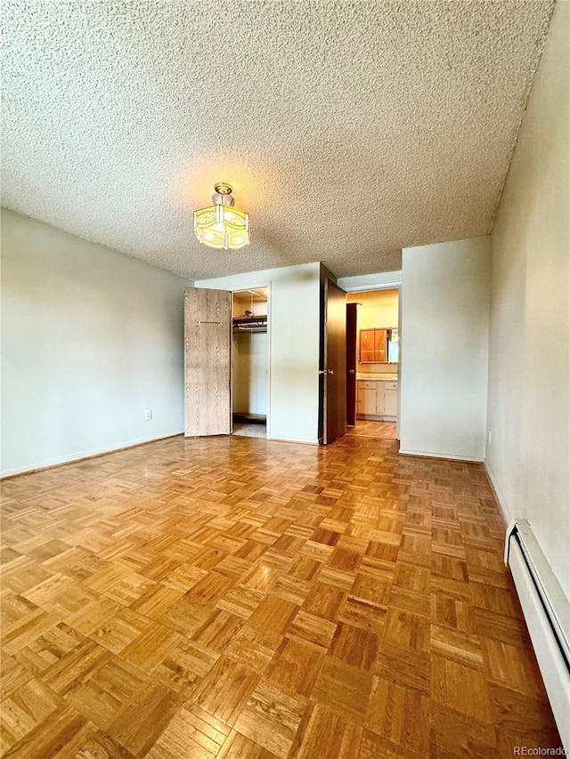 unfurnished room featuring a textured ceiling, baseboard heating, and parquet floors