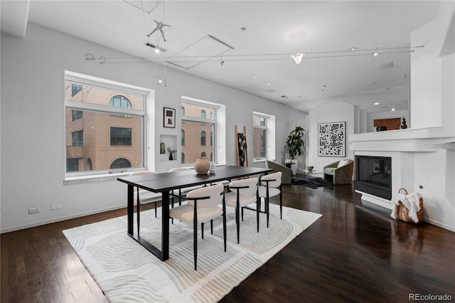 dining space with baseboards, attic access, a glass covered fireplace, and wood finished floors