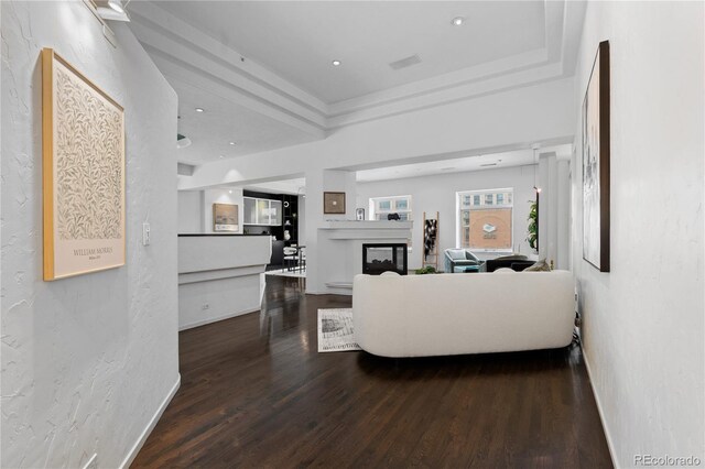 living area with wood finished floors, a glass covered fireplace, and a textured wall