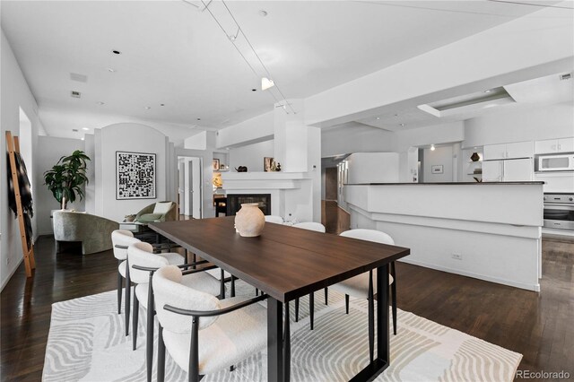 dining space with a glass covered fireplace, visible vents, baseboards, and wood finished floors