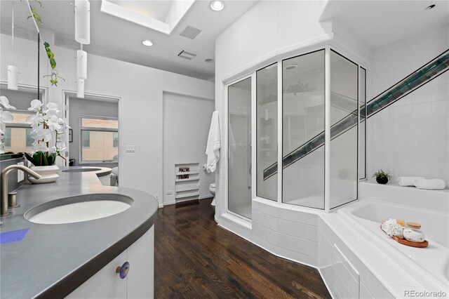 full bath featuring double vanity, recessed lighting, a shower stall, a sink, and wood finished floors