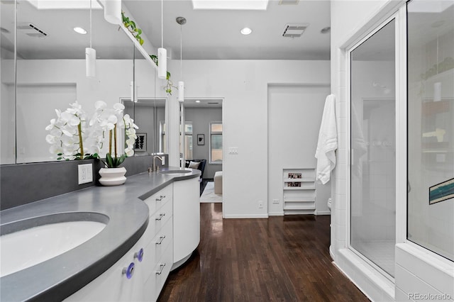 bathroom with a sink, hardwood / wood-style flooring, recessed lighting, double vanity, and a stall shower