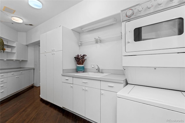 laundry area featuring a sink, dark wood-style floors, visible vents, and stacked washer / drying machine