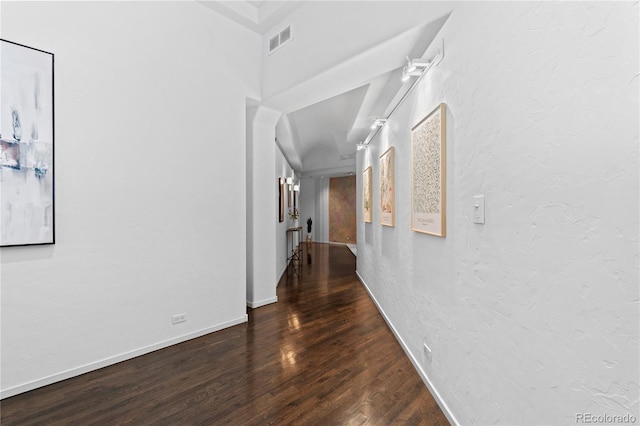 corridor with wood finished floors, a textured wall, and visible vents