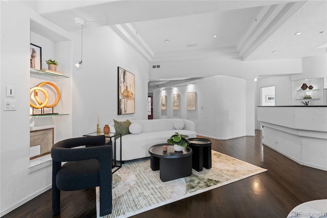 living area with visible vents, baseboards, a raised ceiling, and wood finished floors