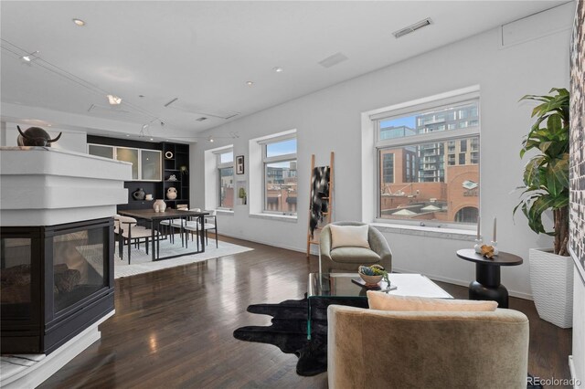 living room with visible vents, a wealth of natural light, a multi sided fireplace, and wood finished floors