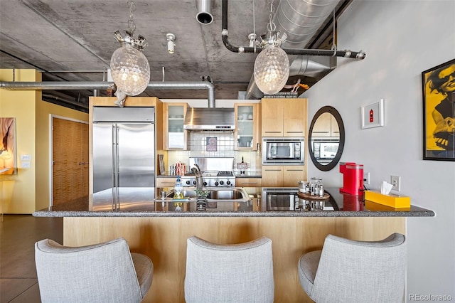 kitchen with sink, decorative backsplash, exhaust hood, built in appliances, and light brown cabinets