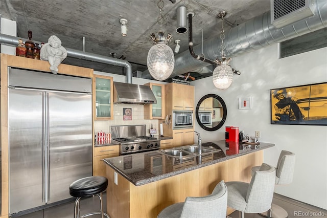 2100 16th St Unit 606, Denver, CO 80202 - kitchen featuring built in appliances, a breakfast bar, a sink, a peninsula, and wall chimney range hood