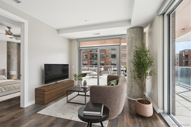 living area featuring visible vents, baseboards, wood finished floors, and floor to ceiling windows