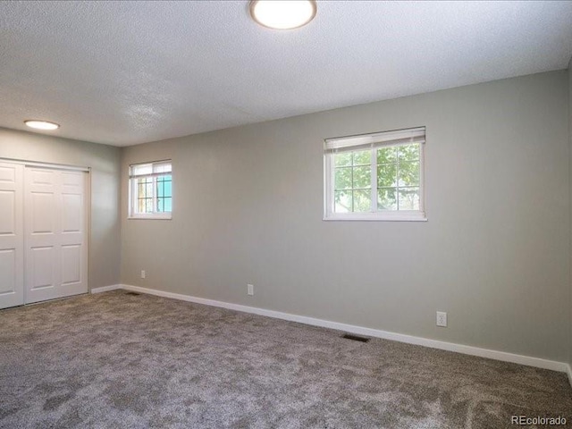 unfurnished bedroom featuring a closet, a textured ceiling, baseboards, visible vents, and carpet floors