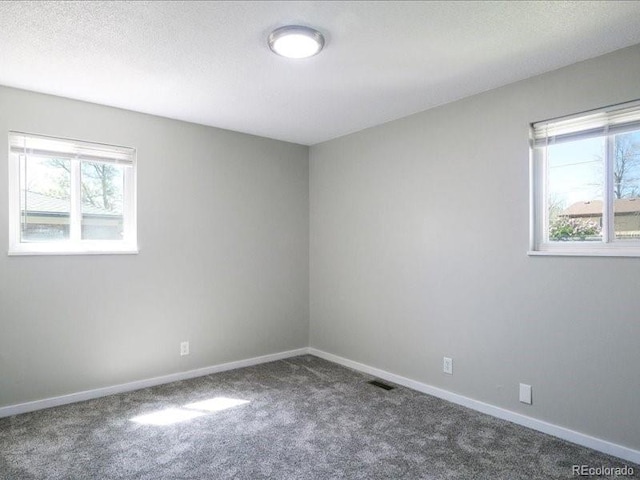 carpeted spare room featuring baseboards and visible vents