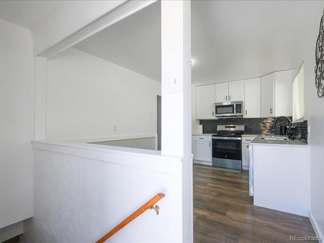 kitchen featuring a sink, stainless steel appliances, white cabinets, dark wood-type flooring, and tasteful backsplash