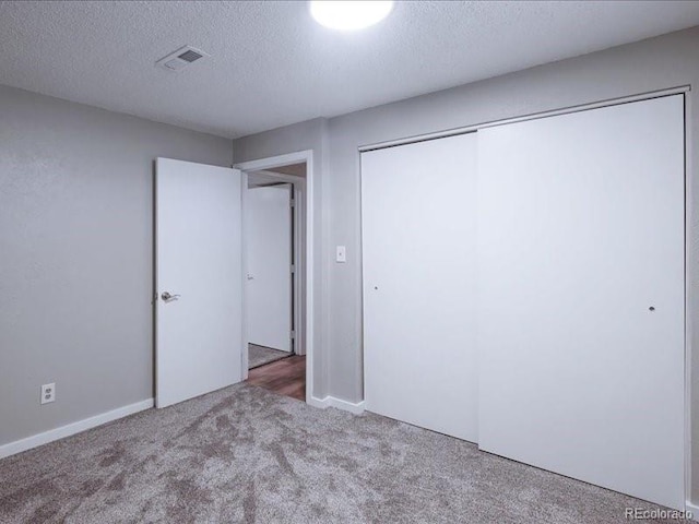 unfurnished bedroom featuring a textured ceiling, a closet, visible vents, and carpet floors