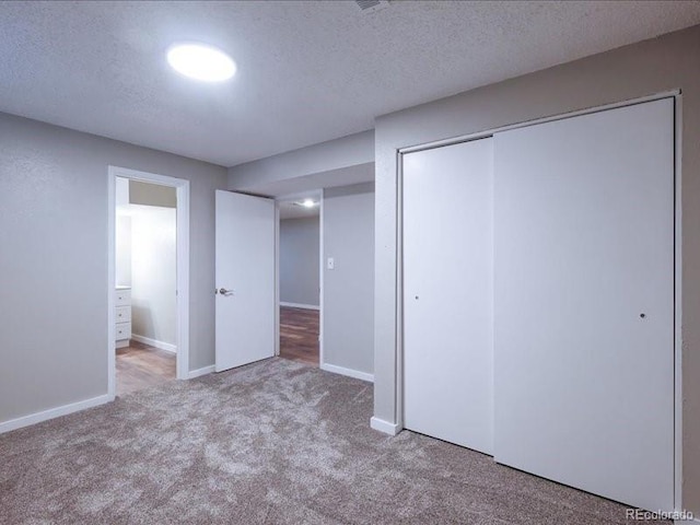 unfurnished bedroom with a textured ceiling, carpet, a closet, and baseboards
