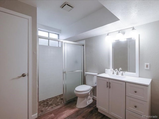 bathroom featuring a stall shower, toilet, visible vents, vanity, and wood finished floors