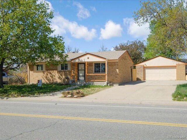 ranch-style home featuring concrete driveway, brick siding, and a detached garage