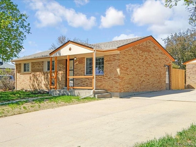 ranch-style house featuring a porch, fence, and brick siding