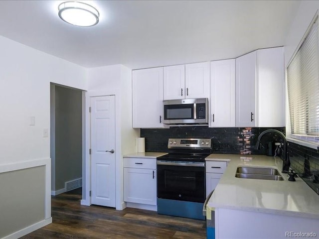 kitchen with stainless steel appliances, a sink, white cabinetry, backsplash, and light countertops