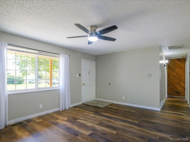 spare room featuring wood finished floors, a textured ceiling, visible vents, baseboards, and ceiling fan