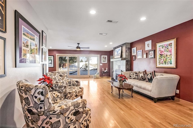 living room with a fireplace, light hardwood / wood-style floors, and ceiling fan