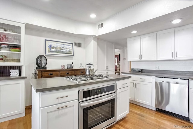 kitchen with stainless steel appliances, white cabinetry, a center island, and light hardwood / wood-style floors