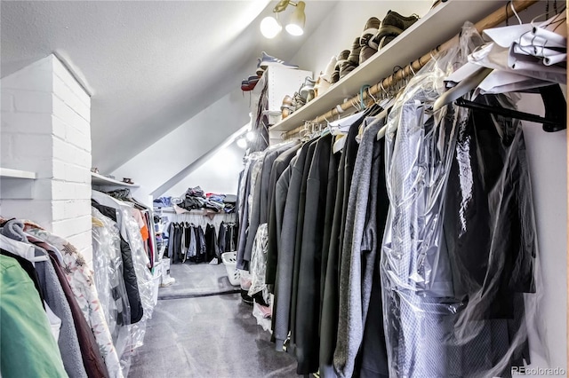 walk in closet with vaulted ceiling and carpet flooring