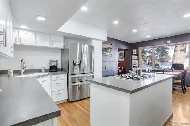 kitchen featuring a kitchen island, recessed lighting, white cabinetry, a sink, and stainless steel appliances