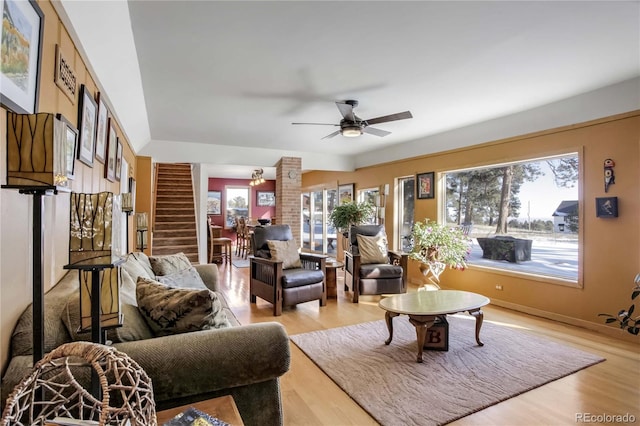 living room featuring a ceiling fan, light wood-style flooring, and stairs