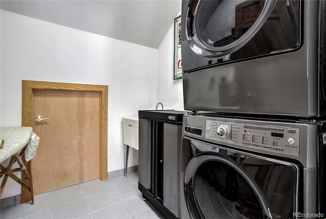 laundry area with light tile patterned floors, laundry area, and stacked washer / dryer