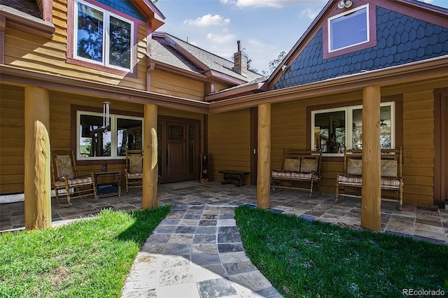 view of exterior entry featuring a patio and a chimney