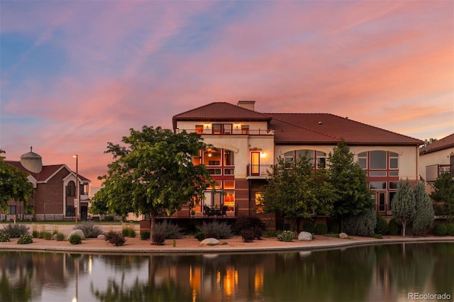 back house at dusk with a balcony