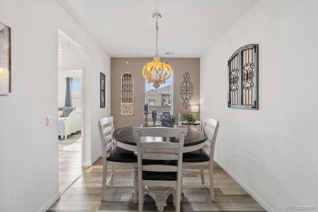 dining room featuring light wood-style floors, visible vents, plenty of natural light, and an inviting chandelier