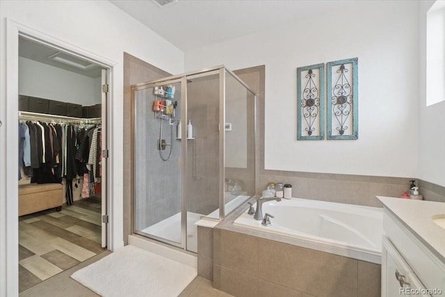 full bath featuring a stall shower, a spacious closet, vanity, and a bath