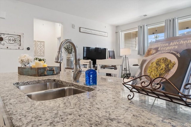 kitchen with light stone countertops, visible vents, and a sink