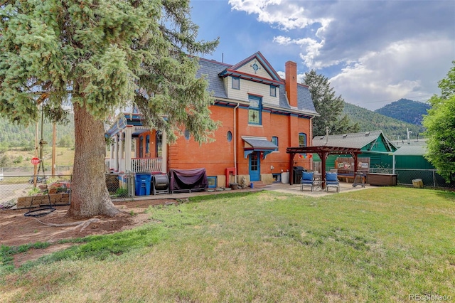 rear view of house featuring a mountain view, a yard, a patio, and a pergola