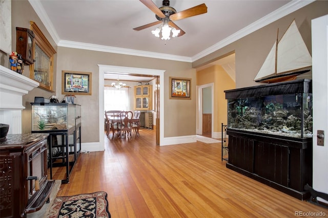 living room with hardwood / wood-style flooring, ceiling fan with notable chandelier, and crown molding