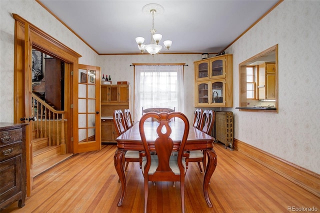 dining space with ornamental molding, light wood-type flooring, and a notable chandelier