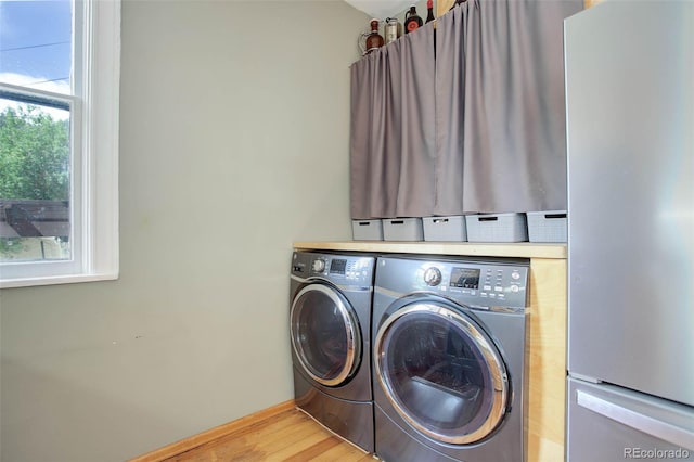 clothes washing area with light hardwood / wood-style floors and washing machine and dryer