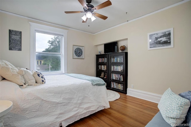 bedroom with hardwood / wood-style floors, ceiling fan, and ornamental molding